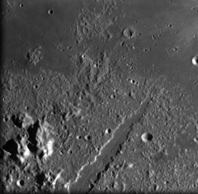 The Lunar Alps
Original caption:"The European Alps were formed over millions of years by slow-moving sections of Earth’s crust pushed together, squeezing the land to form a giant arc of upthrust mountains, but the Lunar Alps were formed in an instant. It is thought that the Moon collided with a huge object, such as an asteroid, 3850 million years ago. The collision formed a huge crater, about 1000 Km in diameter. This crater was later filled with basaltic lava, forming the dark circular basin known as Mare Imbrium (Sea of Rains). After the explosive collision, fragments, rocks and dust fell back to the surface. While there is considerable debate as to the actual mechanism which formed the concentric rings, it is agreed they are not 'fallback' material. Some scientists argue that the the impact caused the lower layers to act as a liquid and that the rings then 'froze' in place. A flood of lava covered the lower inner one, but the outer one remains as a series of arc-shaped mountain ranges. 
In places these mountains rise over 3000 metres. Their inner walls are steep and well defined, but their outer slopes become more broken as elevation decreases away from the impact site. Early European astronomers named them after familiar mountain ranges, such as the Juras, the Apennines and the Alps. 

Seen in this image, Vallis Alpes (Alpine Valley) is a spectacular feature that bisects the Montes Alpes range. This valley was discovered in 1727 by Francesco Bianchini. It extends 166 kilometres from Mare Imbrium, trending north-east to the edge of the Mare Frigoris (Sea of Cold). The valley is narrow at both ends and widens to about 10 kilometres across. 

The valley floor is a flat, lava-flooded surface that has narrow sinous ‘rille’ running down the middle. It is generally considered to be a 'graben', an area between two parallel faults which has dropped below the surrounding area. This is believed to have formed after the formation of the basin, but before the full maria lava flows. The rille corresponds to a ‘lava tube’ formed in a later geological episode by high-speed and low viscosity magma. 

"SMART-1 is studying the signature of violent processes that took place during the formation of these giant impact basins, as well as the sequence of late volcanic history over the lunar surface until 3000 million years ago,” said ESA’s SMART-1 Project Scientist Bernard Foing. 

Parole chiave: The Moon from orbit - SMART-1