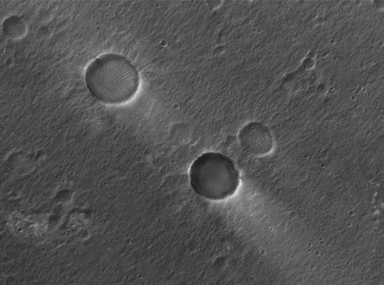 Signs of the wind in Chryse Planitia (Original NASA/MGS/MSSS b/w Frame)
Caption NASA originale:"This MGS-MOC image shows two Unnamed Impact Craters of nearly equal size, plus their associated Windstreaks. These occur in far Eastern Chryse Planitia. The Wind streaks point toward the South-West, indicating that the responsible Winds blew from the North-East. One of the two craters is shallower than the other and has a suite of large, windblown Ripples on its Floor. The shallower Unnamed Crater with the Ripples is probably older than the other, deeper Unnamed Crater".  

Location near: 20,6° North Lat. and 30,1° West Long.
Image width: ~3 Km (~1,9 mi)  
Illumination from: lower left  
Season: Northern Winter
Parole chiave: Mars from orbit - Craters - Unnamed Craters - Chrise Planitia Region