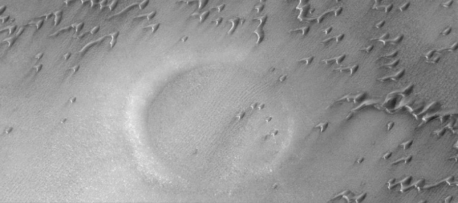 Under the Sand (Original NASA/MGS/MSSS b/w Frame)
Caption NASA originale:"This MGS-MOC image shows a partially-buried crater in the North Polar Region of Mars. 
The circular feature is surrounded and partly overlain by some of the many, many sand dunes in the area. The steepest slopes on each dune — their "slip faces" — face toward the SouthEast, indicating that the dominant winds responsible for sand transport in this Region come from the NorthWest".

Location near: 76,0° North; 82,2° West
Image width: ~3 Km (~1,9 mi)  
Illumination from: lower left  
Season: Northern Spring
Parole chiave: Mars from orbit - North Polar Features - buried crater