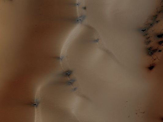 Dunes in Richardson Crater (EDM - Natural Colors; credits for the additional process. and color.: Dr Paolo C. Fienga - Lunexit Team)
This observation from NASA's Mars Reconnaissance Orbiter (MRO) is a view of the Sand Dunefield in Richardson Crater, still partually covered with seasonal frost.

This EDM is a close-up view of defrosting patterns on the Dunes. The frost is a combination of frozen CO2 and some water ice that covers the Dunes in the Winter and Spring. As the seasonal frost sublimes away, odd features such as spots, fans, and streaks form.
Small dark streaks on the dune slip-face slopes may be where recent avalanches of sand, or perhaps wind, has moved the dark sand underlying the frost, or where frost has been removed to expose the sand. Alternatively, the dark streaks may be patches of coarse-grained ice that are clear enough so that the dark material below the ice is visible. 
The slip-faces indicate the general direction of sand transport.

It has been hypothesized that the Dark Spots and Fans may be "geysers" or "cold gas jets" that form when sublimation processes trap gas at the bottom of the ice. The gas is released through cracks in the ice, entraining dust from below the ice and scattering it onto the Surface to form the Dark Spots and Fans.
Parole chiave: Mars from orbit - Craters - Richardson Crater